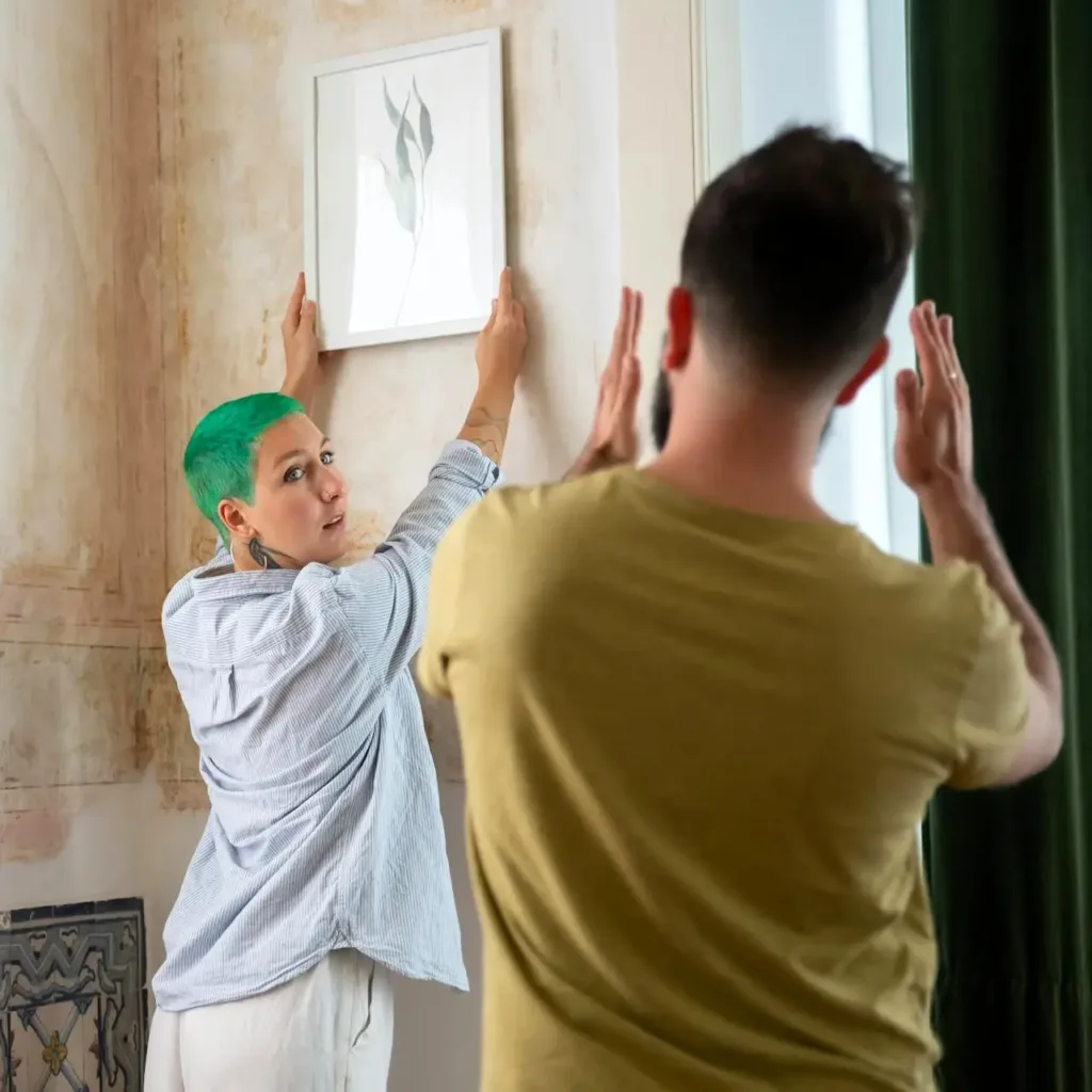 man and woman straightening picture frame