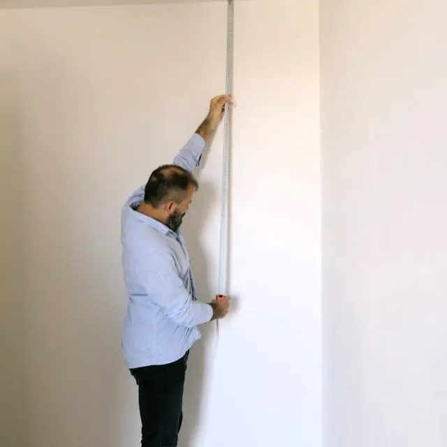man measuring wall