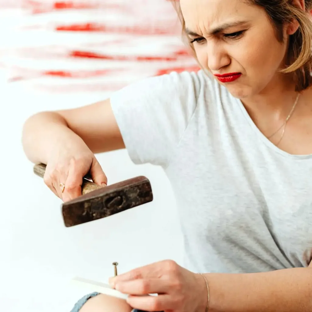 woman knocking nail with hammer